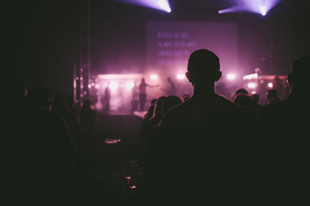 Silhouettes of an audience in front of a lit stage